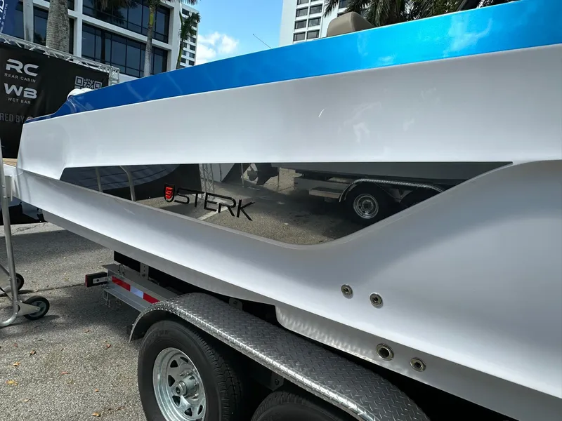 Slide: The Image of 2025 STERK 31 WB Sport boat on trailer, sleek white and blue design. - 12