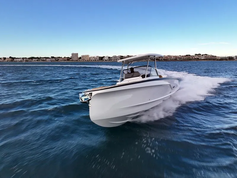 Slide: The Image of 2025 STERK 31 WB Sport boat cruising on open water, cityscape in background. - 15