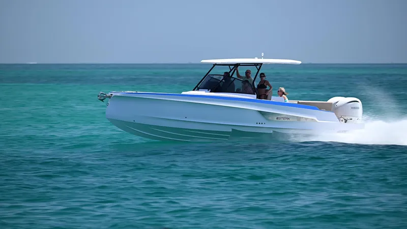 Slide: The Image of 2025 STERK 31 WB Sport boat cruising on clear turquoise water. - 2