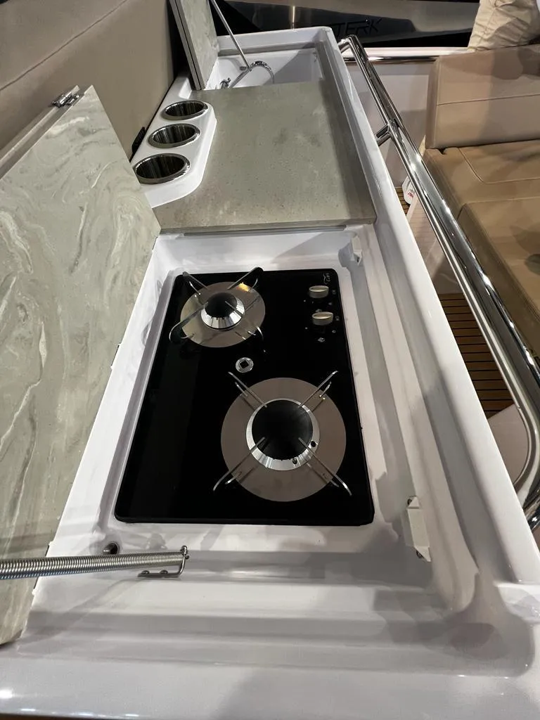 Slide: The Image of 2025 STERK 31 WB Sport boat kitchen with dual-burner stove and countertop. - 49