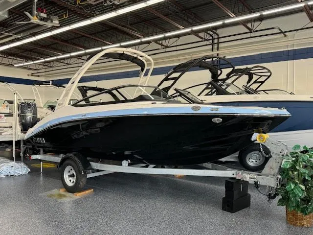 Slide: The Image of 2025 Yamaha Boats 195S in showroom, sleek black design on trailer. - 0