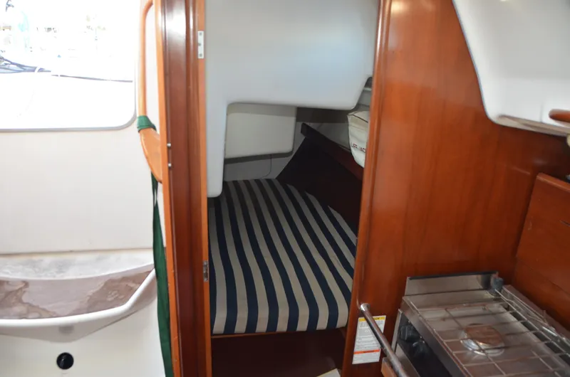 Slide: The Image of Interior cabin of 2002 Beneteau First 36.7 sailboat with striped bedding and wooden finish. - 28