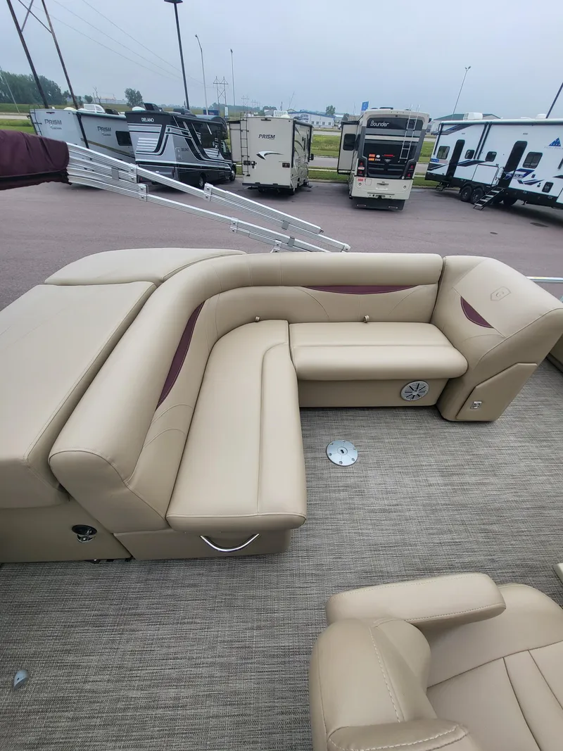 Slide: The Image of 2018 Sweetwater CRUISER boat with beige seating, parked near RVs. - 11