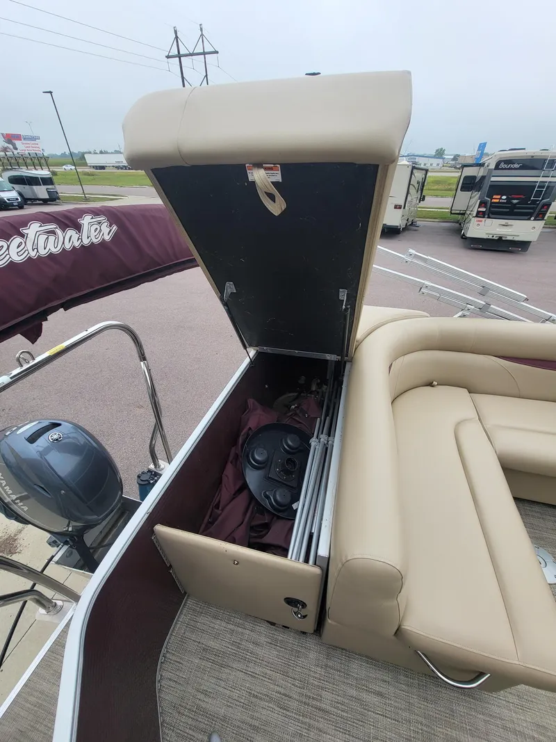 Slide: The Image of 2018 Sweetwater CRUISER boat with open storage compartment and beige seating. - 8