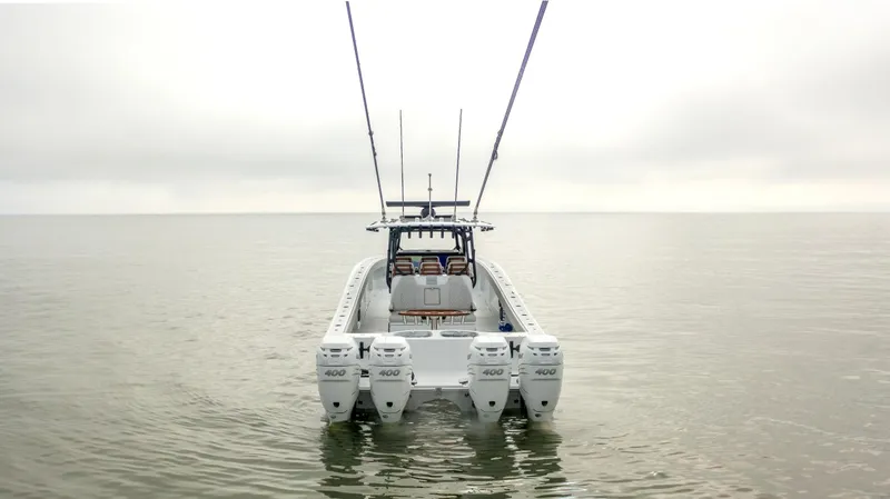 Slide: The Image of 2023 Freeman 42 LR boat with four engines on calm water, viewed from the rear. - 6