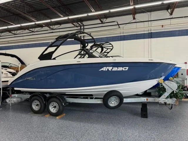 The Image of 2025 Yamaha AR220 boat on trailer in showroom, blue and white design. - 0