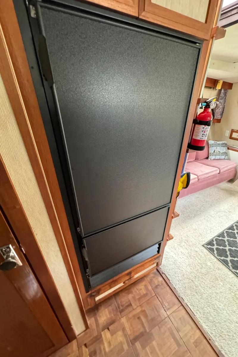 Slide: The Image of 1986 Carver Mariner 3297 interior with black refrigerator and cozy living space. - 10