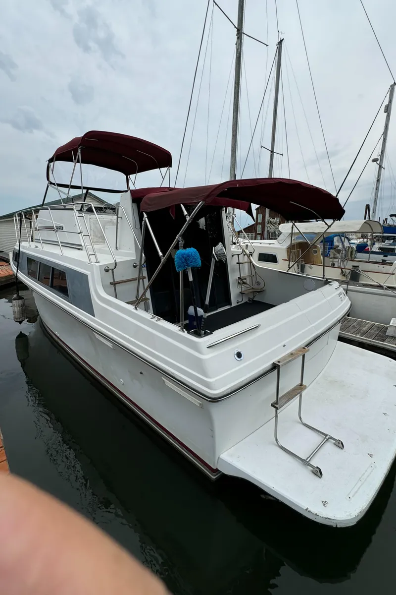 Slide: The Image of 1986 Carver Mariner 3297 boat docked, featuring red canopies and a spacious deck. - 5