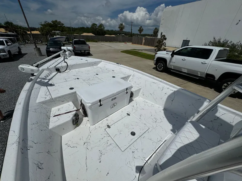 Slide: The Image of 2023 Blazer Bay 2400 boat with white deck and cooler, parked near trucks. - 17