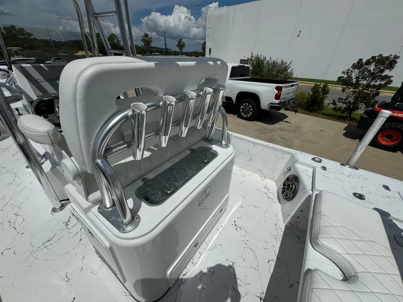 Slide: The Image of 2023 Blazer Bay 2400 boat interior with rod holders and seating, parked outdoors. - 23