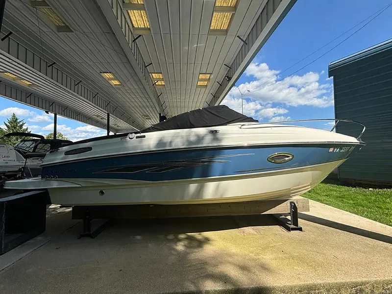 Slide: The Image of 2014 Bayliner 642 Cuddy boat under a covered dock, blue and white exterior. - 2