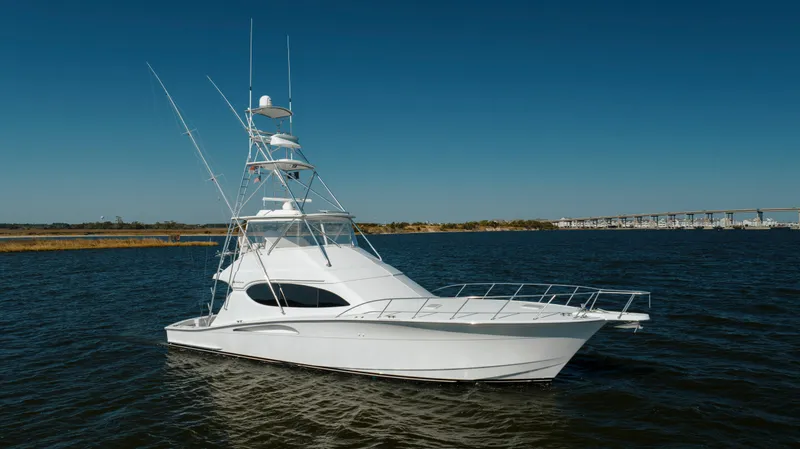 The Image of 2005 Hatteras 54 Convertible yacht on calm water under clear blue sky. - 0