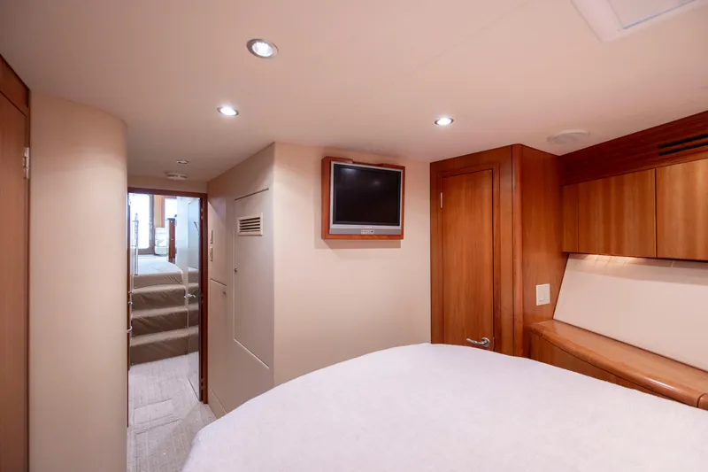 Slide: The Image of Interior of 2005 Hatteras 54 Convertible yacht, featuring cozy bedroom with TV and wood accents. - 34