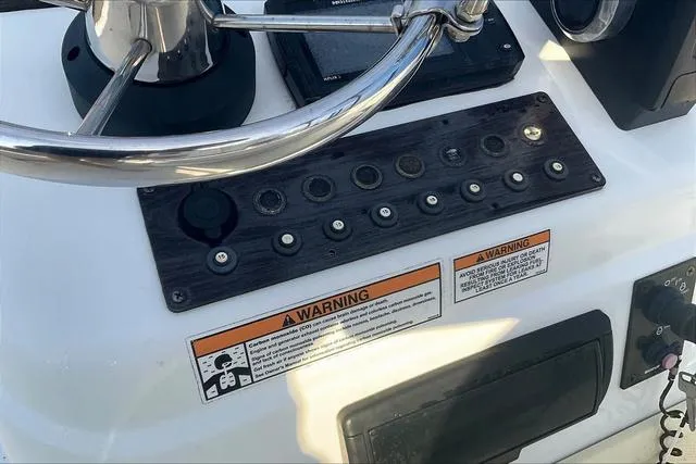 Slide: The Image of Control panel of a 2021 Key Largo 1800 CC boat with steering wheel and warning labels. - 14