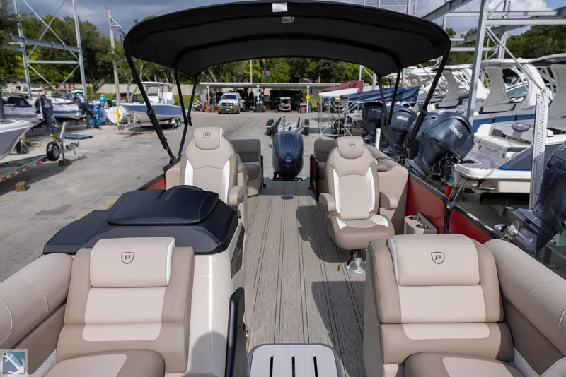 Slide: The Image of 2025 Premier 250 Solaris RF pontoon boat with luxurious seating and canopy in a marina. - 15