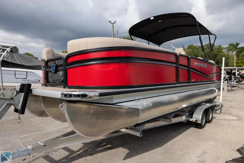 Slide: The Image of 2025 Premier 250 Solaris RF pontoon boat with red exterior on a trailer. - 2