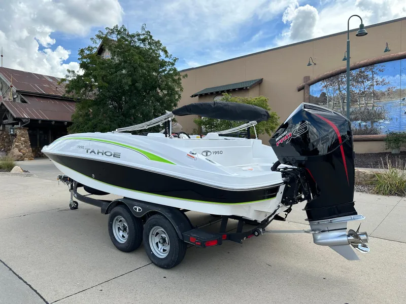 Slide: The Image of 2024 Tahoe 1950 boat on trailer, parked outdoors, featuring sleek design and powerful engine. - 2