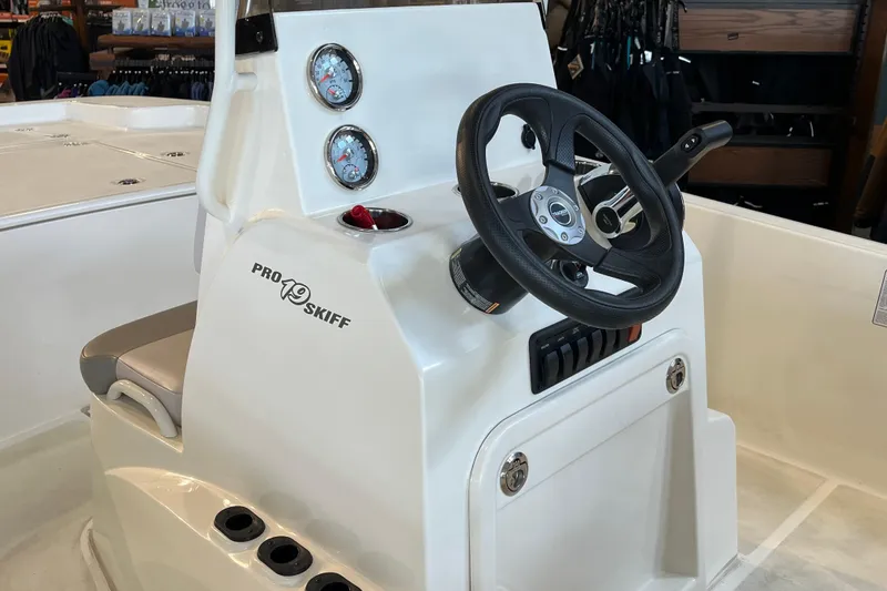 Slide: The Image of 2024 Mako Pro Skiff 19 CC boat on calm water under clear blue sky. - 8