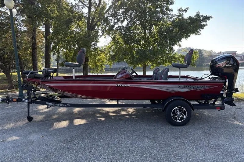 The Image of 2024 Ranger RT188P boat in red, parked on a trailer near a lake. - 0