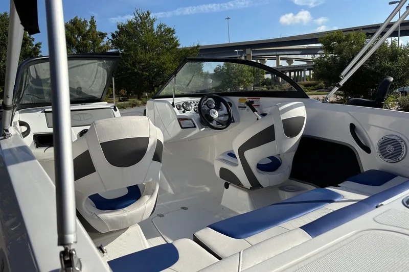 Slide: The Image of 2024 Tahoe 185 S boat interior with modern seating and steering wheel, under a clear sky. - 7