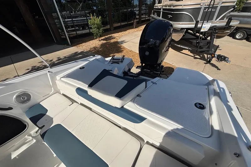 Slide: The Image of 2024 Tahoe 185 S boat interior with seating and motor, parked on a concrete surface. - 9