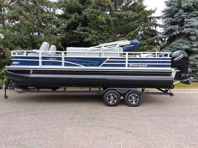 Slide: The Image of 2024 Ranger Reata 220F pontoon boat on trailer, parked near trees. - 2