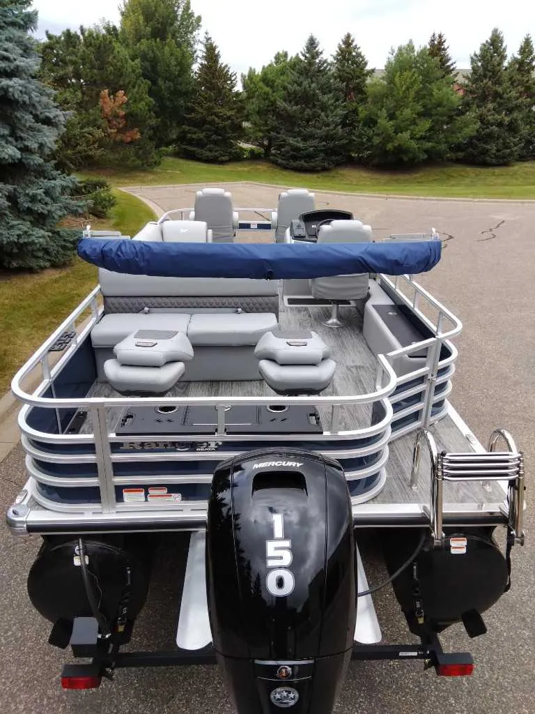 Slide: The Image of 2024 Ranger Reata 220F pontoon boat with 150 HP engine, parked on a road. - 5