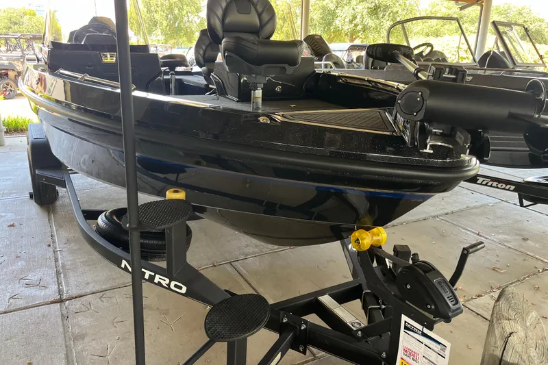 Slide: The Image of 2024 Nitro ZV20 boat on trailer, black exterior, parked under shelter. - 0