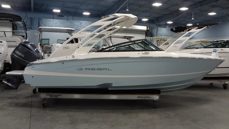 Slide: The Image of 2025 Regal LX2 boat in showroom, side view, light blue and white design. - 1