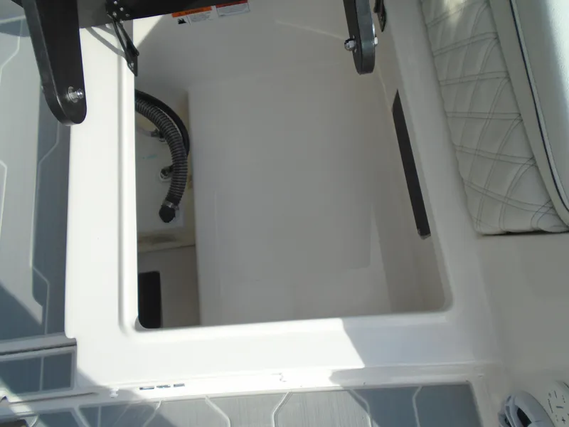 Slide: The Image of 2025 Regal LX2 boat storage compartment with cushioned seating and visible hose. - 17
