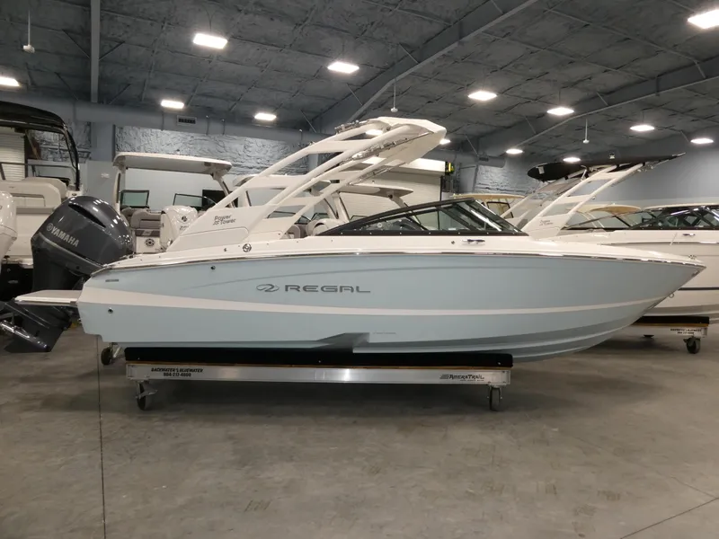 Slide: The Image of 2025 Regal LX2 boat in showroom, sleek design, white hull, modern interior. - 2