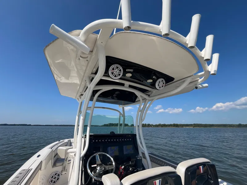 Slide: The Image of 2019 Wellcraft 262 Fisherman boat interior with helm, seats, and rod holders on a sunny day. - 15