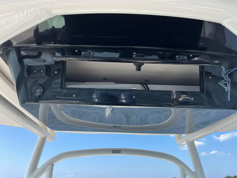 Slide: The Image of 2019 Wellcraft 262 Fisherman boat console with open storage compartment under clear blue sky. - 24