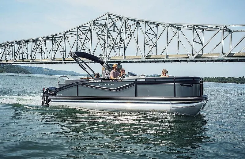 The Image of 2024 Lowe RS230WT pontoon boat cruising under a bridge on a scenic waterway. - 1