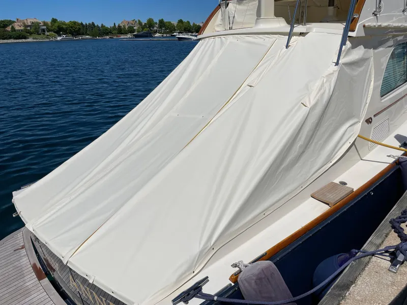 Slide: The Image of 2007 Hinckley Talaria 44 Flybridge with protective cover docked by the water. - 17
