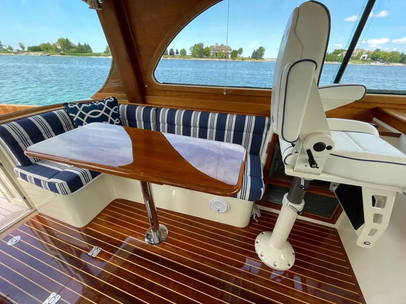 Slide: The Image of 2007 Hinckley Talaria 44 Flybridge interior with striped seating, wooden table, and scenic water view. - 7