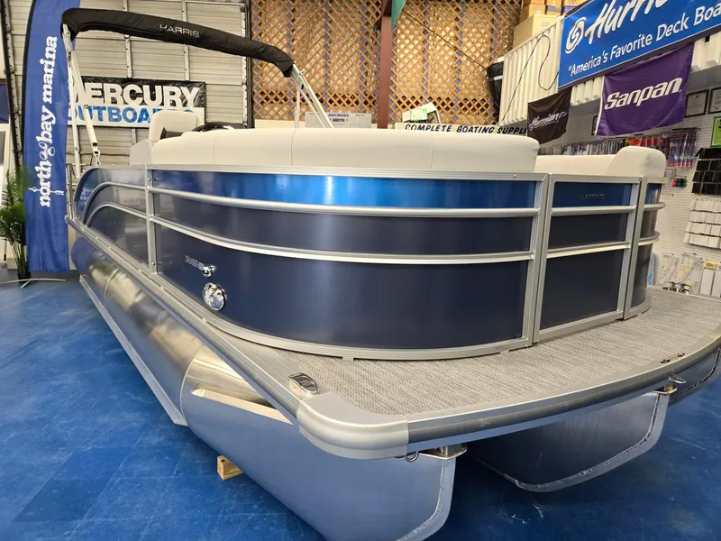 The Image of 2025 Harris Cruiser 210 pontoon boat in showroom, featuring sleek blue and silver design. - 0