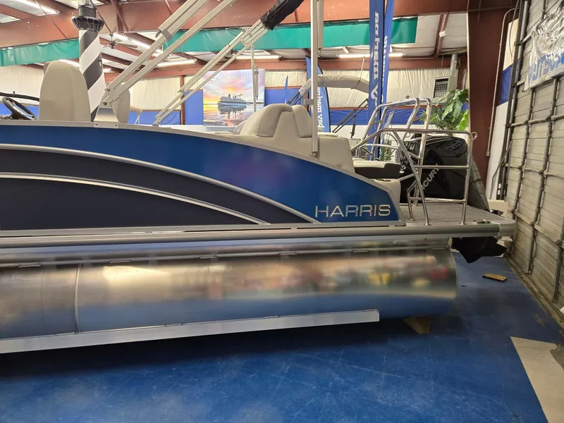 Slide: The Image of 2025 Harris Cruiser 210 pontoon boat in showroom, featuring sleek blue design. - 6