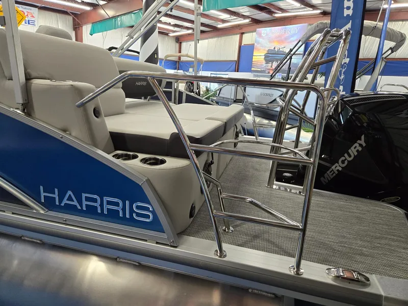 Slide: The Image of 2025 Harris Cruiser 210 pontoon boat interior with seating and railing in showroom. - 7