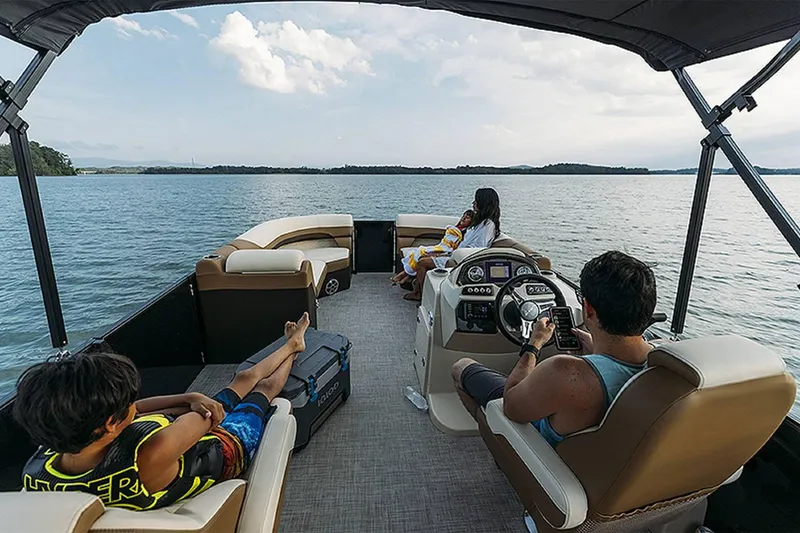 Slide: The Image of 2024 Lowe SS 210 WT pontoon boat cruising on a serene lake with passengers relaxing. - 12