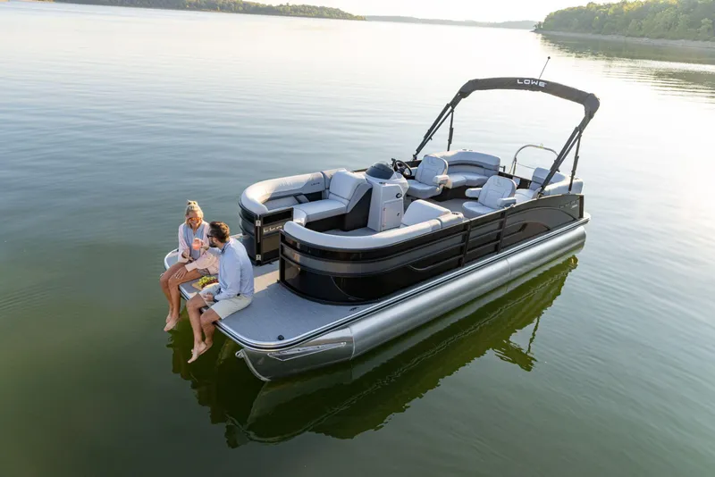 The Image of 2024 Lowe SS 230 WV pontoon boat on calm lake with two people relaxing. - 1
