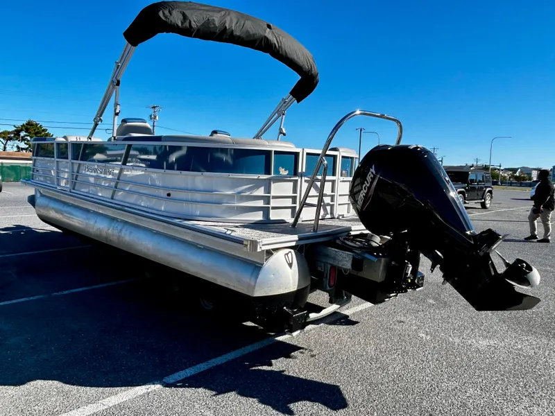Slide: The Image of 2024 Berkshire 24RFX LE 2.75 pontoon boat with outboard motor in a parking lot. - 5