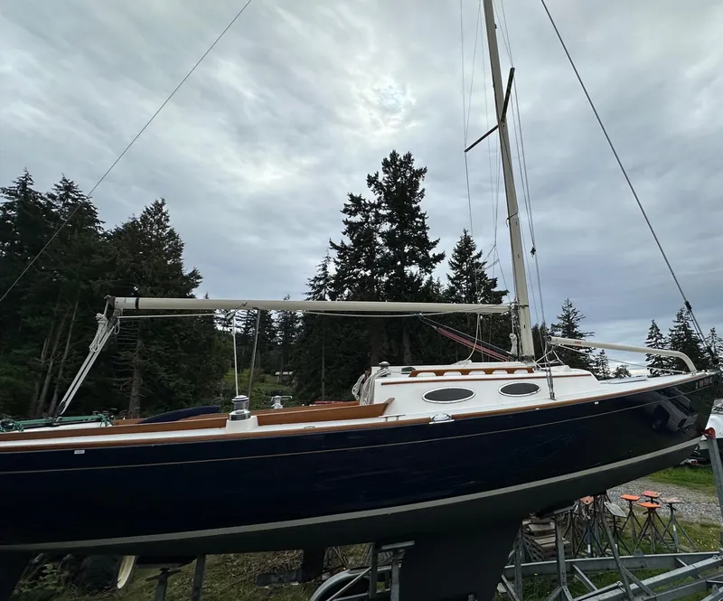 Slide: The Image of 2005 Express Alerion sailboat on land, surrounded by trees under cloudy sky. - 28