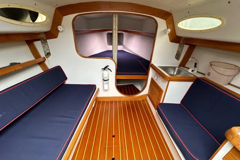 Slide: The Image of Interior of 2005 Express Alerion sailboat with wooden flooring and blue cushioned seating. - 33