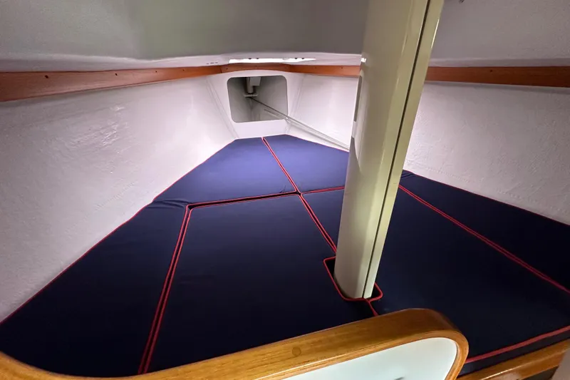 Slide: The Image of 2005 Express Alerion sailboat interior with blue cushioned berth and wooden trim. - 35