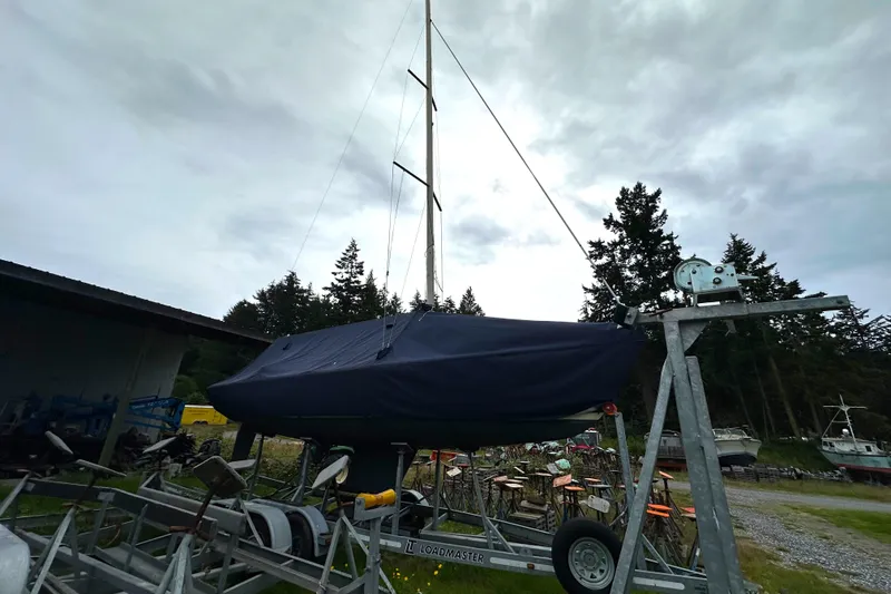 Slide: The Image of 2005 Express Alerion sailboat covered on trailer, surrounded by trees and equipment. - 4