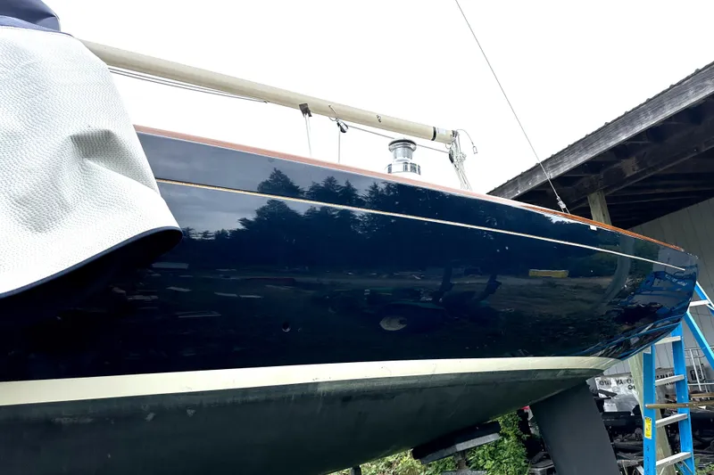 Slide: The Image of 2005 Express Alerion sailboat with dark blue hull, docked under a shelter. - 9