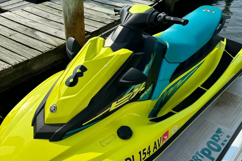 Slide: The Image of 2022 Yamaha WaveRunner EX Sport in vibrant yellow and teal, docked by wooden pier. - 2