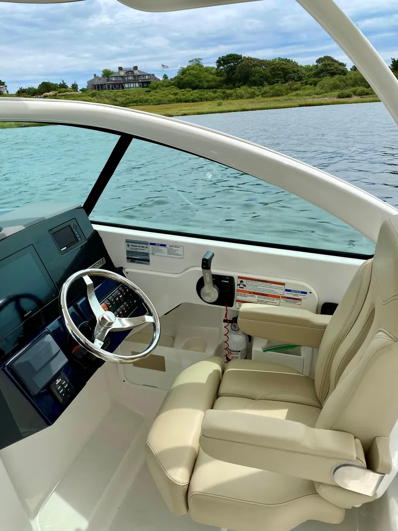 Slide: The Image of 2021 Pursuit DC 235 Dual Console boat interior with steering wheel and comfortable seating. - 10