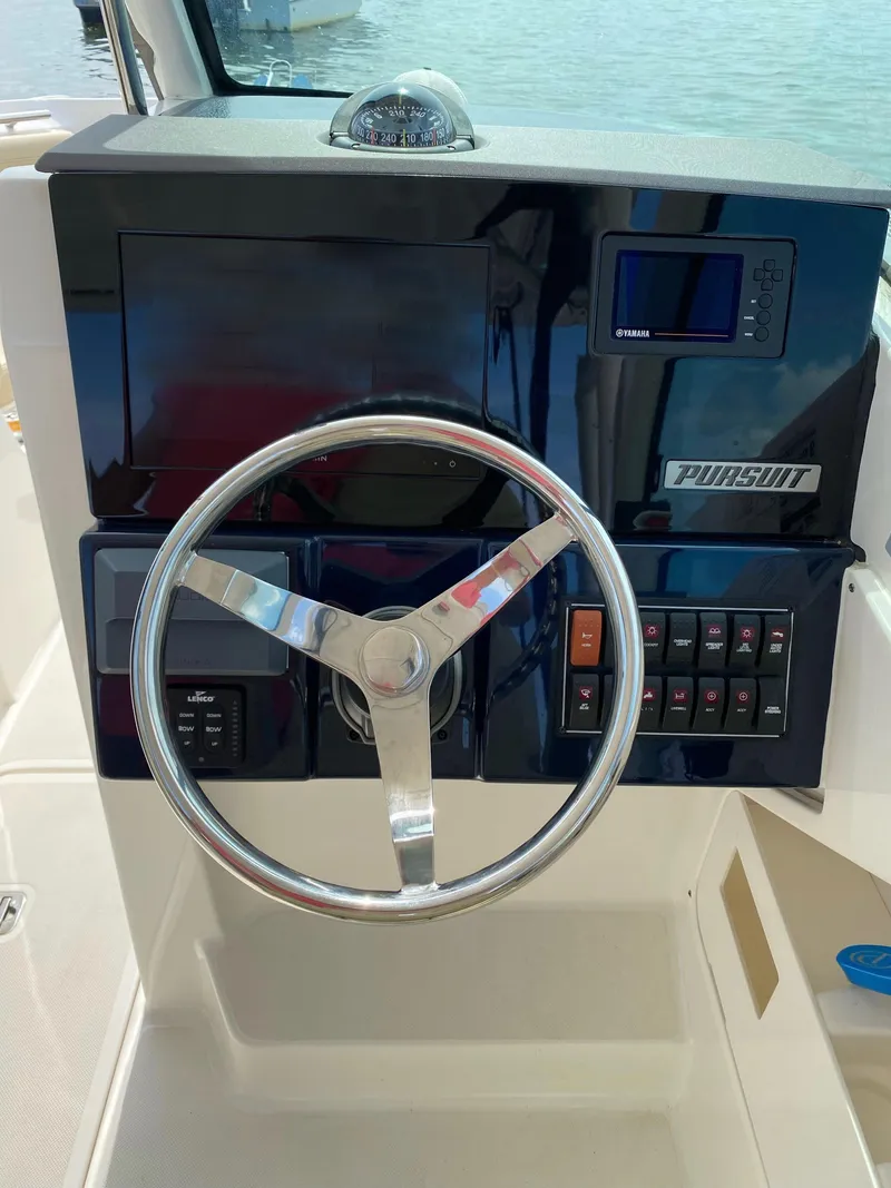 Slide: The Image of 2021 Pursuit DC 235 Dual Console boat dashboard with steering wheel and controls. - 11